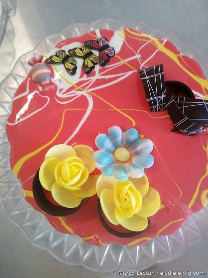 Rote Eistorten-Dekoration mit dekorativen Schmetterlingen, gelben Rosen und blauer Blume aus Zuckerpaste