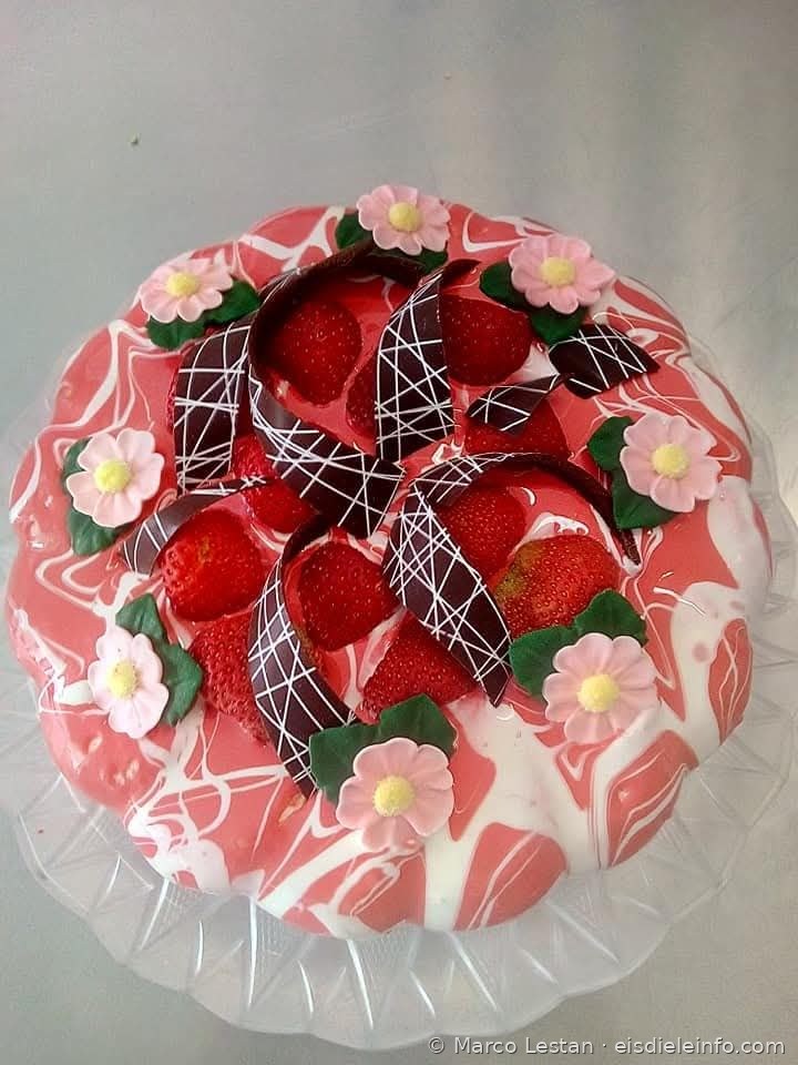Rosa marmorierte Eistorten-Dekoration mit Erdbeeren, Blumen aus Zuckerpaste und Schokoladenbändern