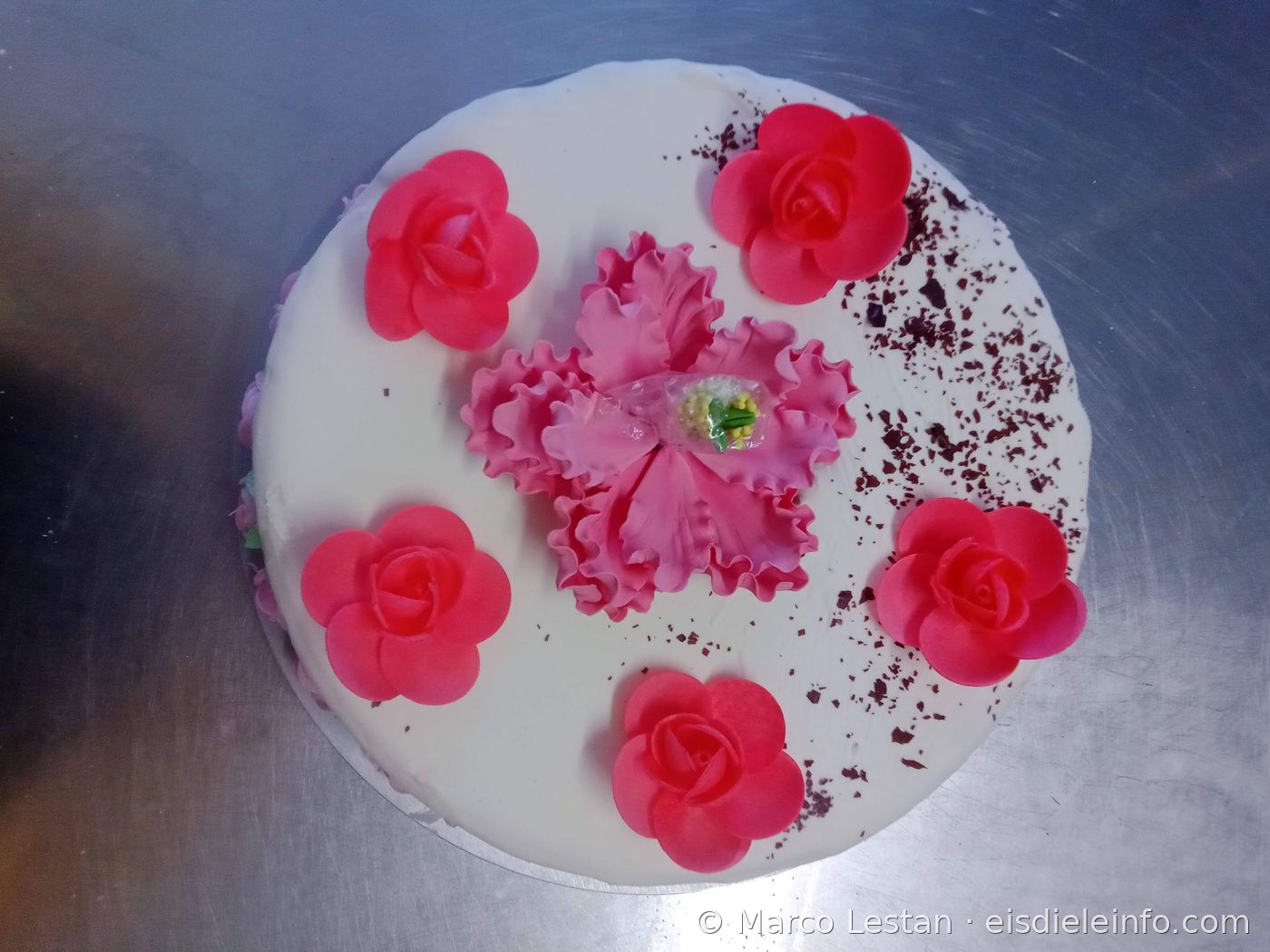 Weiße Eistorten-Dekoration mit rosa Rosen aus Zuckerpaste und zentraler Blume