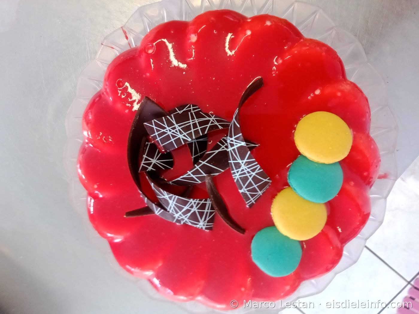 Rote Eistorten-Dekoration mit dekorierter Schokoladenspirale und gelben und türkisen Macarons