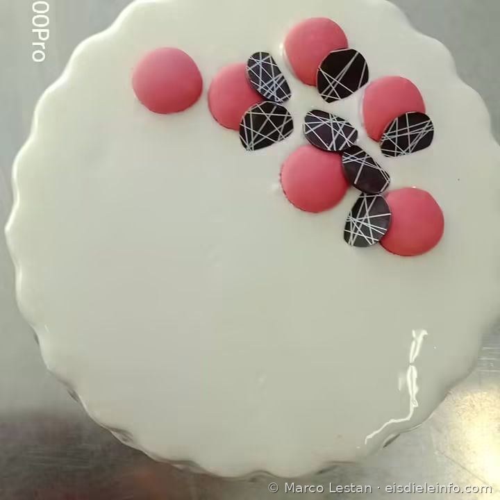 Weiße Eistorte mit rosa Macarons und dekorierten Schokoladenscheiben