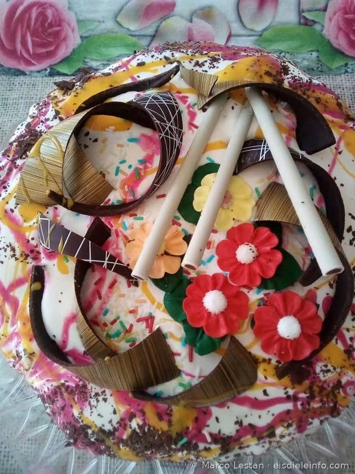 Weiße Eistorte mit bunten Variegatos, Blumen aus Zuckerpaste und Schokoladen-Strohhalmen