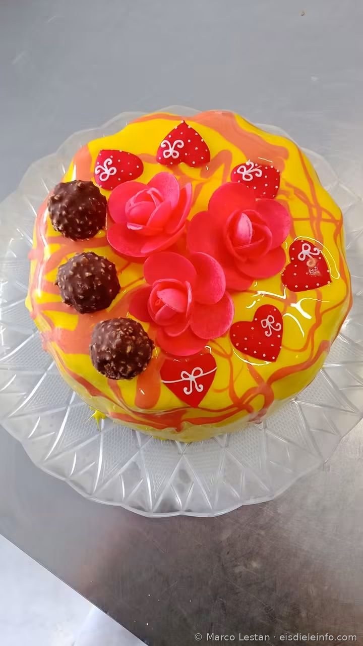 Eistorte mit gelber Glasur, Zuckerpasterosen, roten Herzchen und Schokoladenpralinen