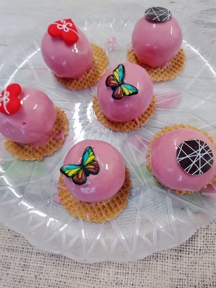 Rosa glasierte Einzelportionen auf Waffel mit roten Herzen, Schmetterlingen und Schokoladenscheiben