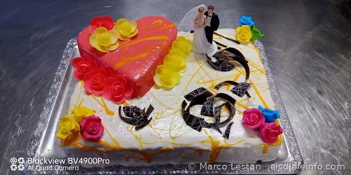 Rechteckige Torte mit rosa Herz, bunten Rosen und Schokoladenspänen aus einem anderen Blickwinkel